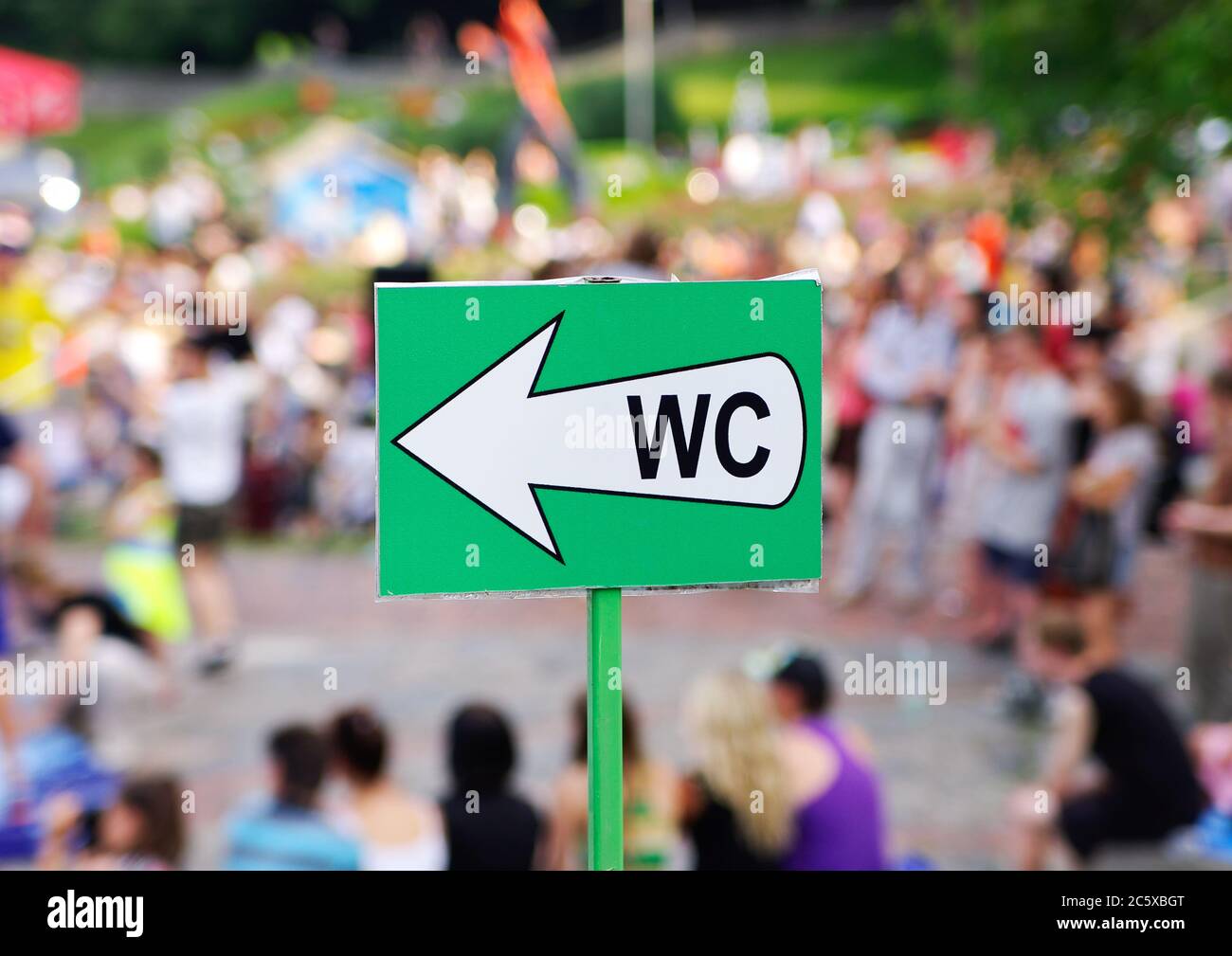 White arrow water closet (WC) sign against blurred  crowd of people Stock Photo