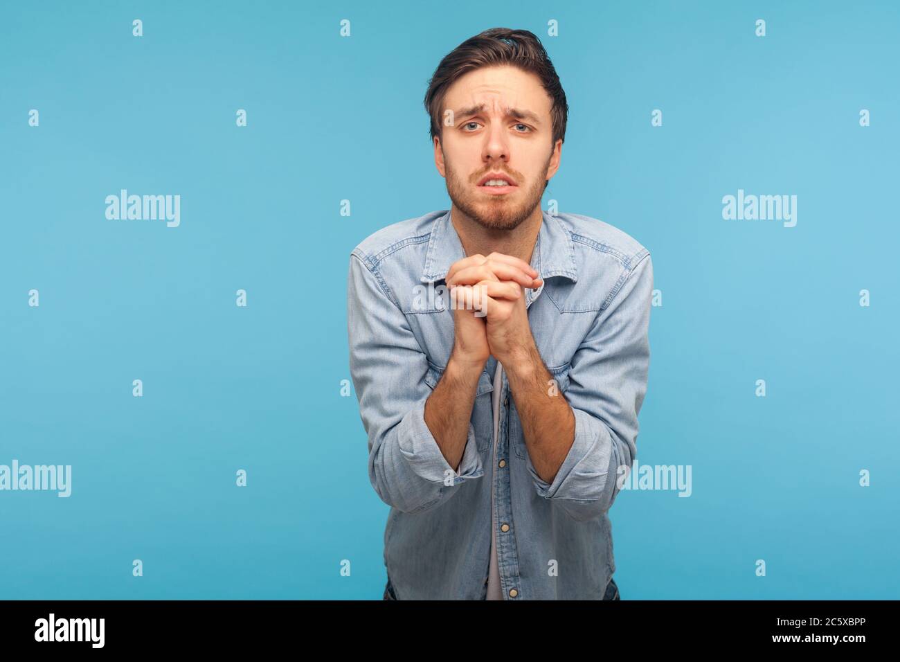 Please, I'm begging! Portrait of unhappy man in worker denim shirt ...