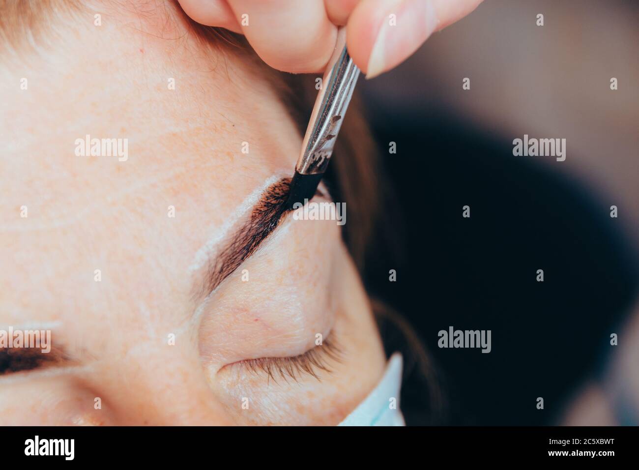 Cosmetic procedure. Correction and coloring of the eyebrows, shaping the eyebrows. Selective focus. Stock Photo