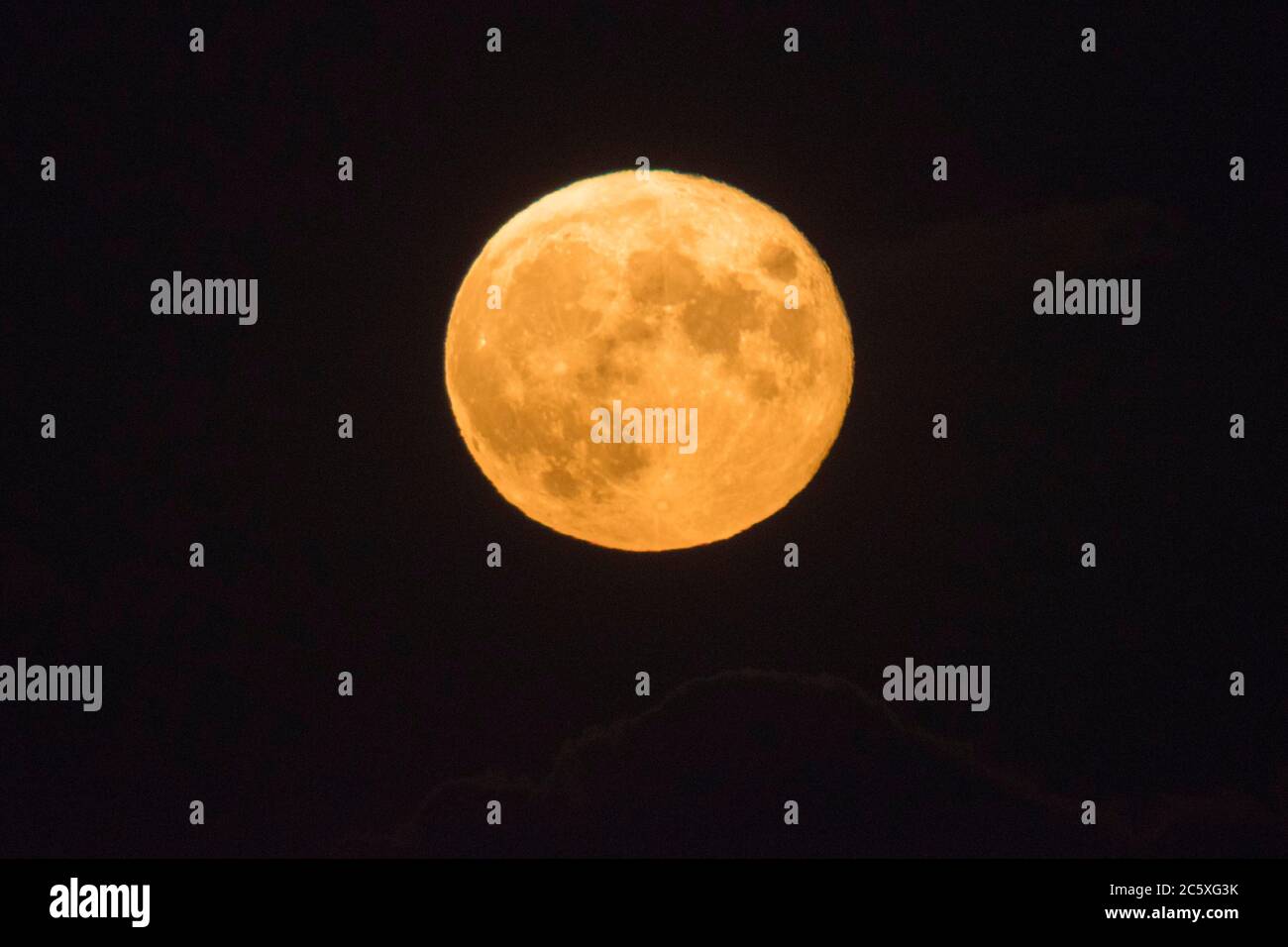 Highcliffe, Dorset, UK.  5th July 2020.  UK Weather. The full Buck Moon glows orange, viewed from Highcliffe in Dorset shortly after moonrise.  Picture Credit: Graham Hunt/Alamy Live News Stock Photo
