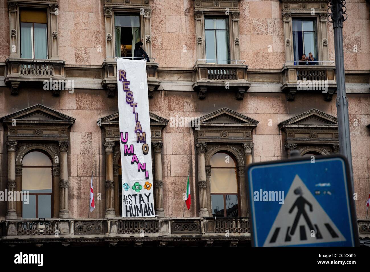 On a balcony above the 'Piazza del Duomo' an activist wearing a Zorro costume showing a protest banner during a political meeting with Matteo Salvini. Stock Photo