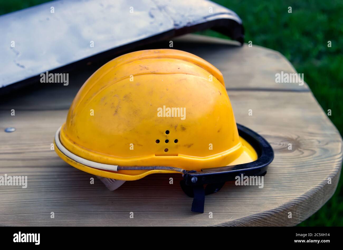 Dirty orange workman's safety helmet (hard hat) on wooden table Stock Photo