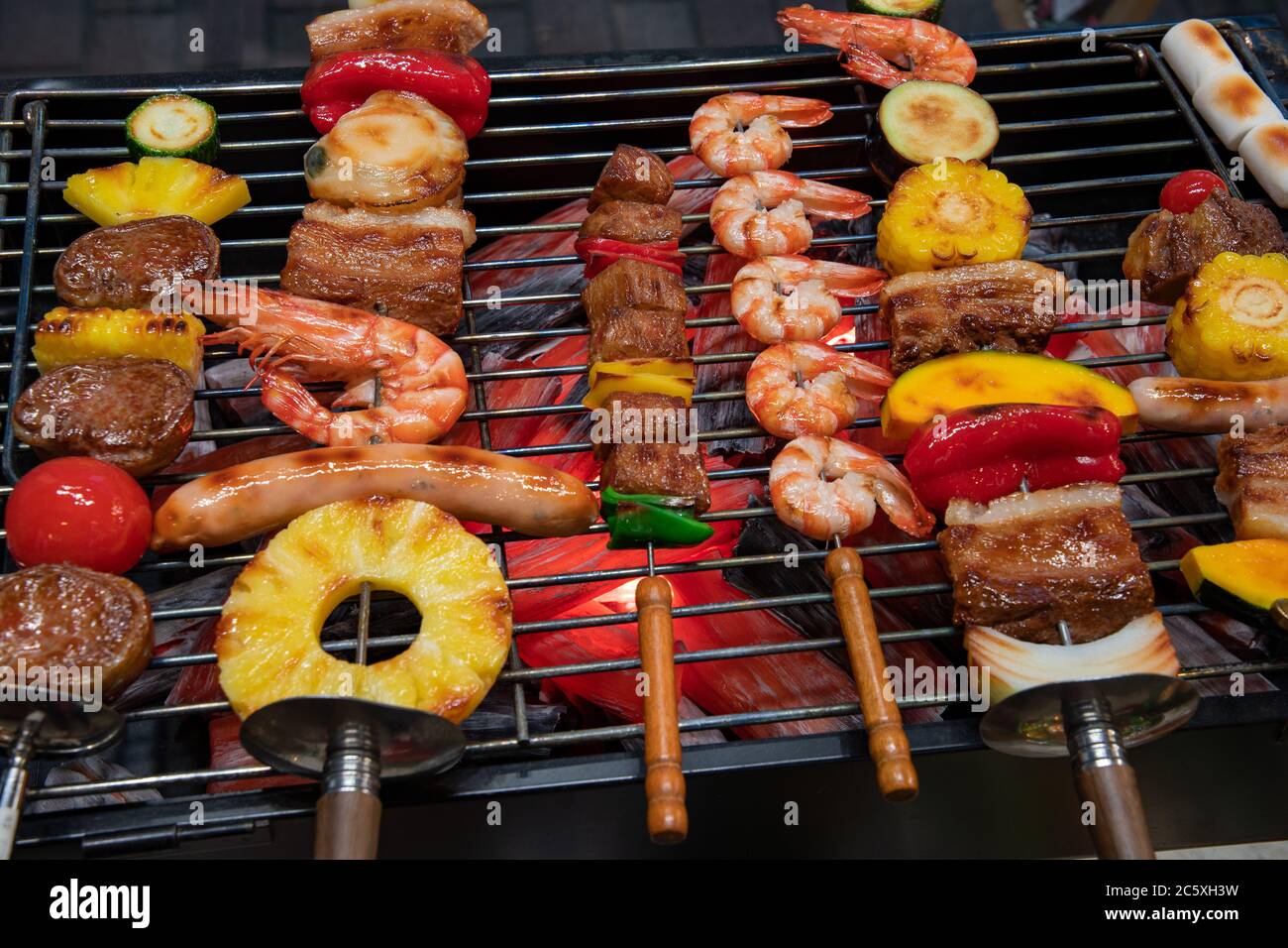 Close-up on a bbq grill with shrimps, ananas, meat and vegetable. Artificial food made by wax. Shop window display, restaurant menu food sample. Stock Photo