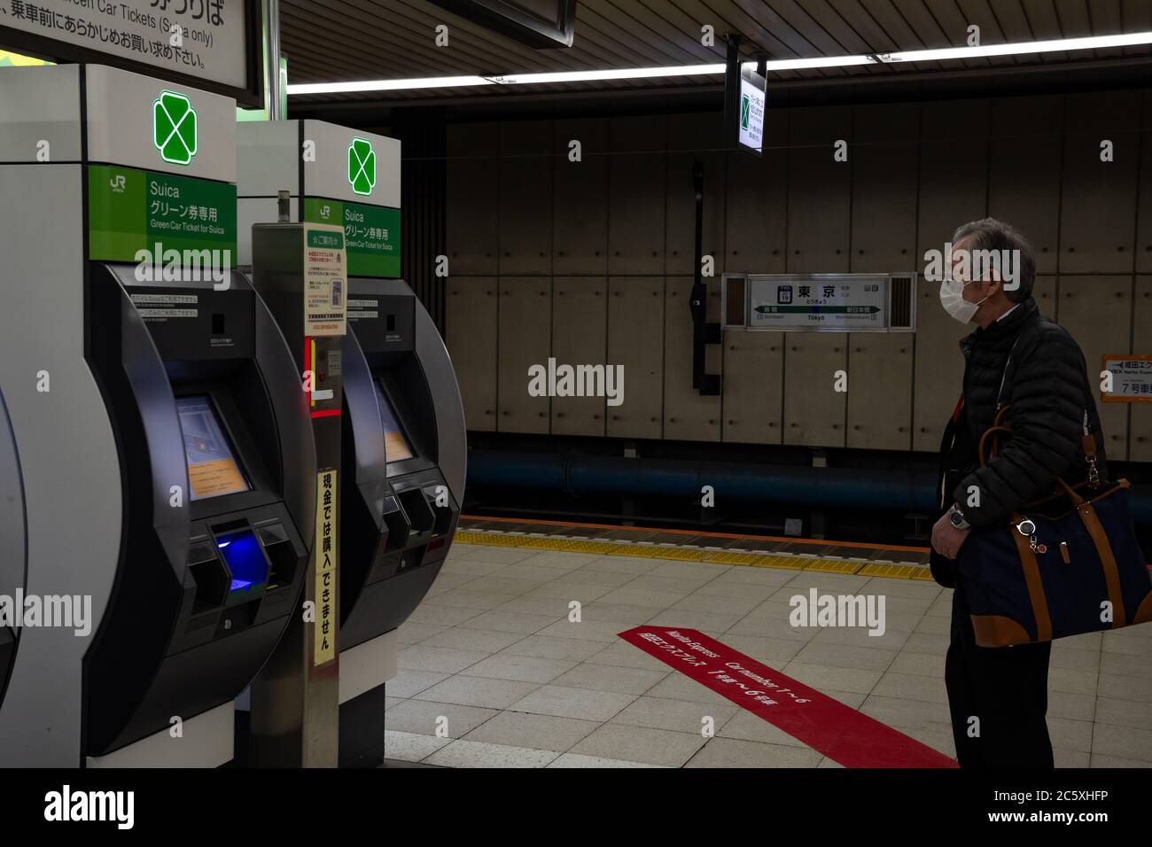 An elderly Japanese man wearing a face mask approachs a Suica vending machine at a platform in Tokyo Station. Tokyo, Japan. Stock Photo
