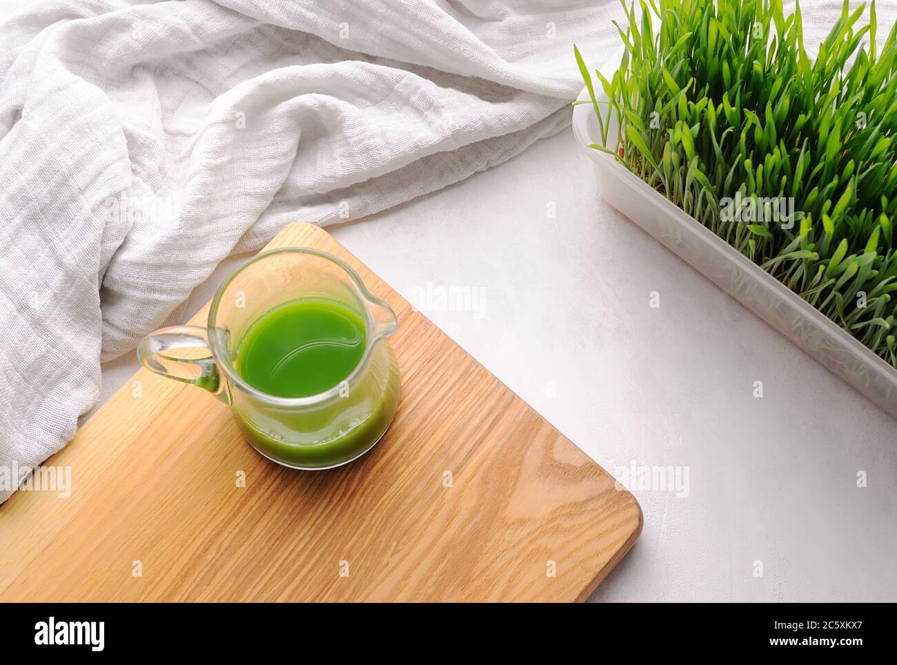 Wheat grass shot on the wooden board and wheat grass plant in the pot.Modern trend of health. Stock Photo