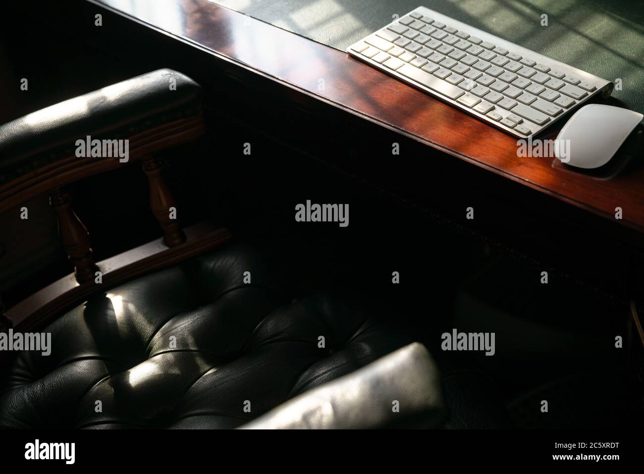 Computer keyboard on wood and leather table. Light play forming lines and shadows. Copy space. Stock Photo