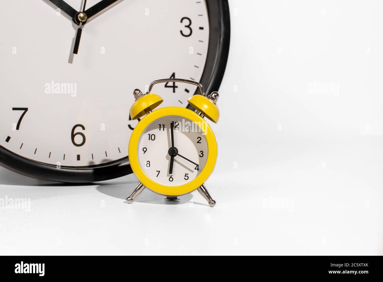 Small time clock in white background and big clock behind Stock Photo