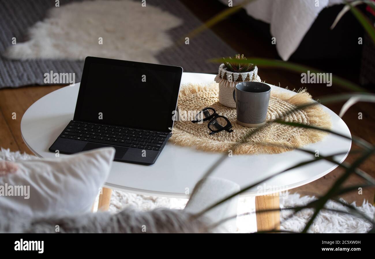 Working from home on laptop at coffee table Stock Photo