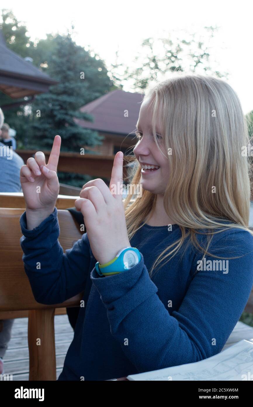 Young preteen girl smiling and in conversation gesturing with her fingers. Spala Central Poland Stock Photo