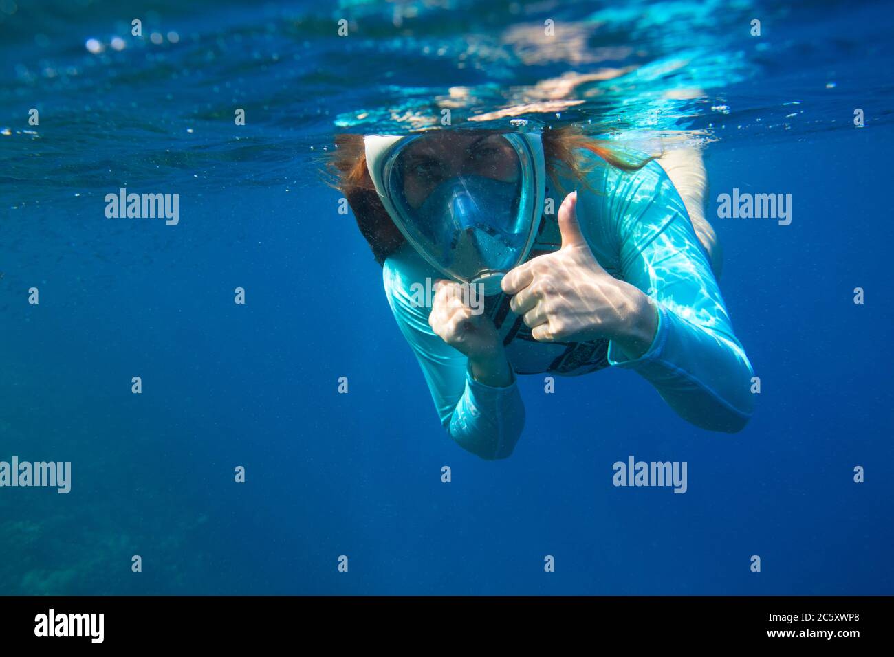 Young woman in snorkeling mask underwater photo. Female snorkel show thumb undersea. Snorkeling