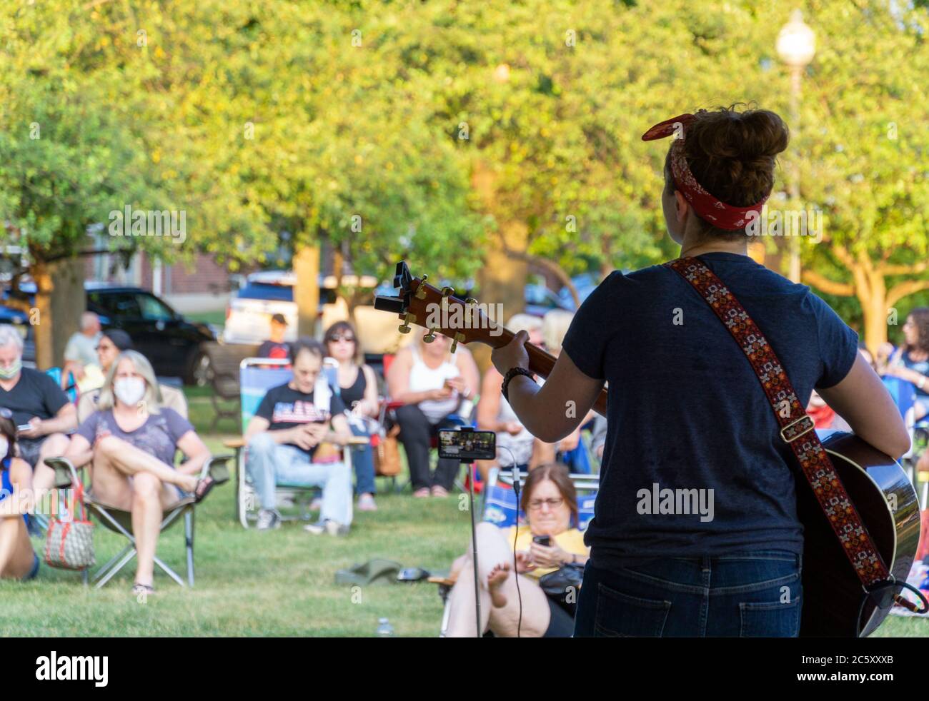 McGowan Park Summer Concerts - Sandy Stones Trio Band - Woman playing guitar in front of coronavirus crowd Stock Photo