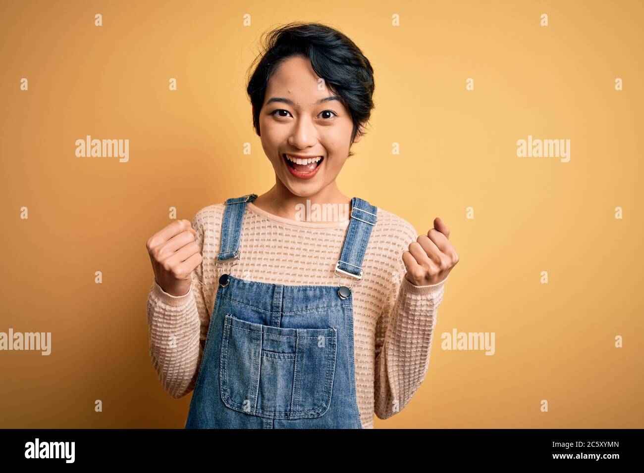 Young beautiful asian girl wearing casual denim overalls over isolated ...
