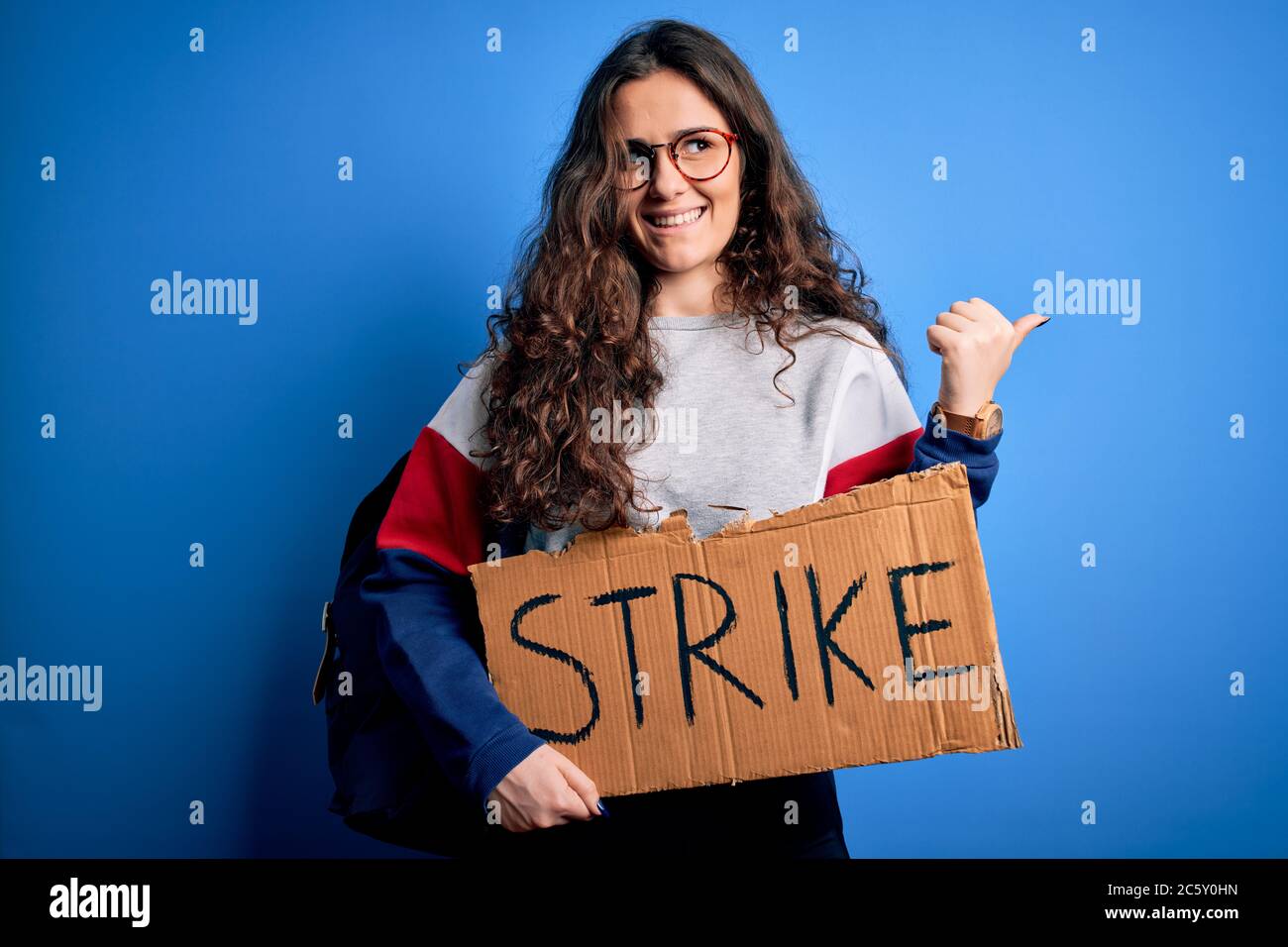 Beautiful student woman with curly hair wearing backpack holding banner ...