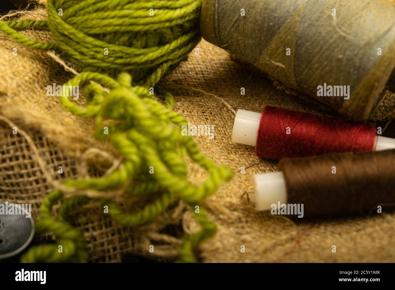 Various buttons and multicolored threads on coarse-textured burlap. Close up Stock Photo