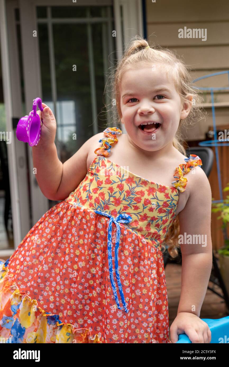 Three year old girl having fun playing outside with her water toys. Stock Photo