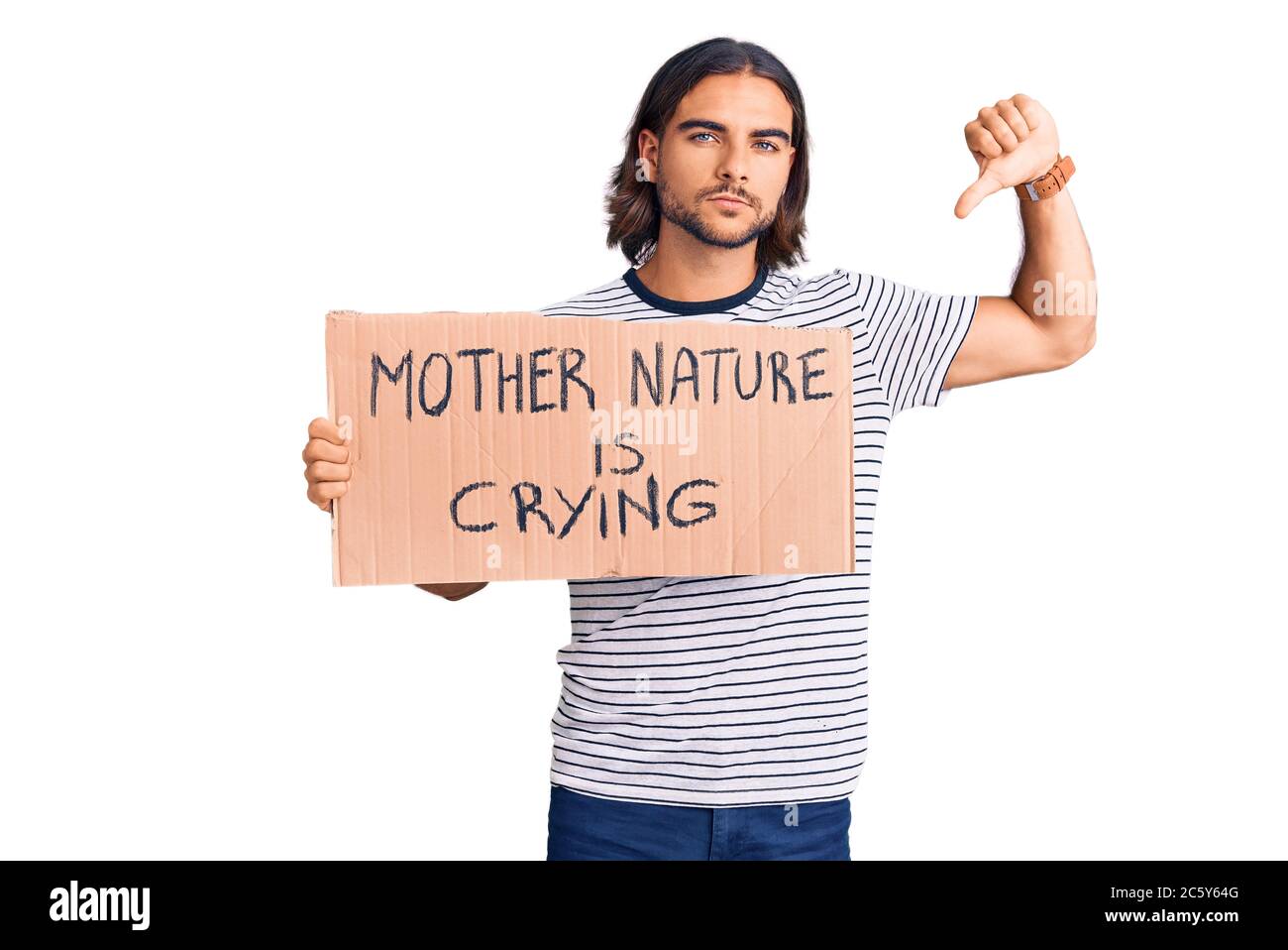 Young handsome man holding mother nature is crying protest cardboard banner with angry face, negative sign showing dislike with thumbs down, rejection Stock Photo