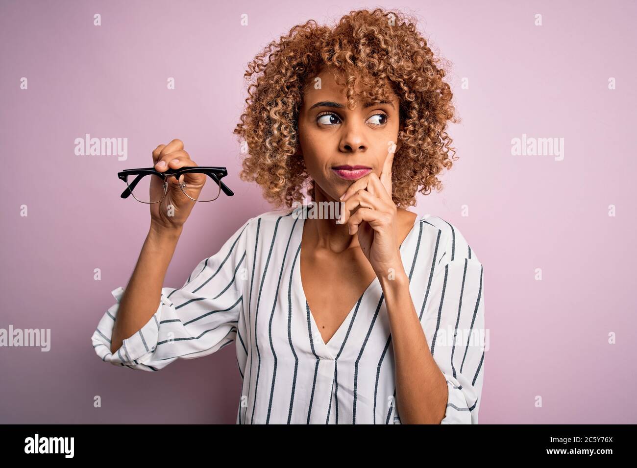 African american optical woman with curly hair holding glasses over ...