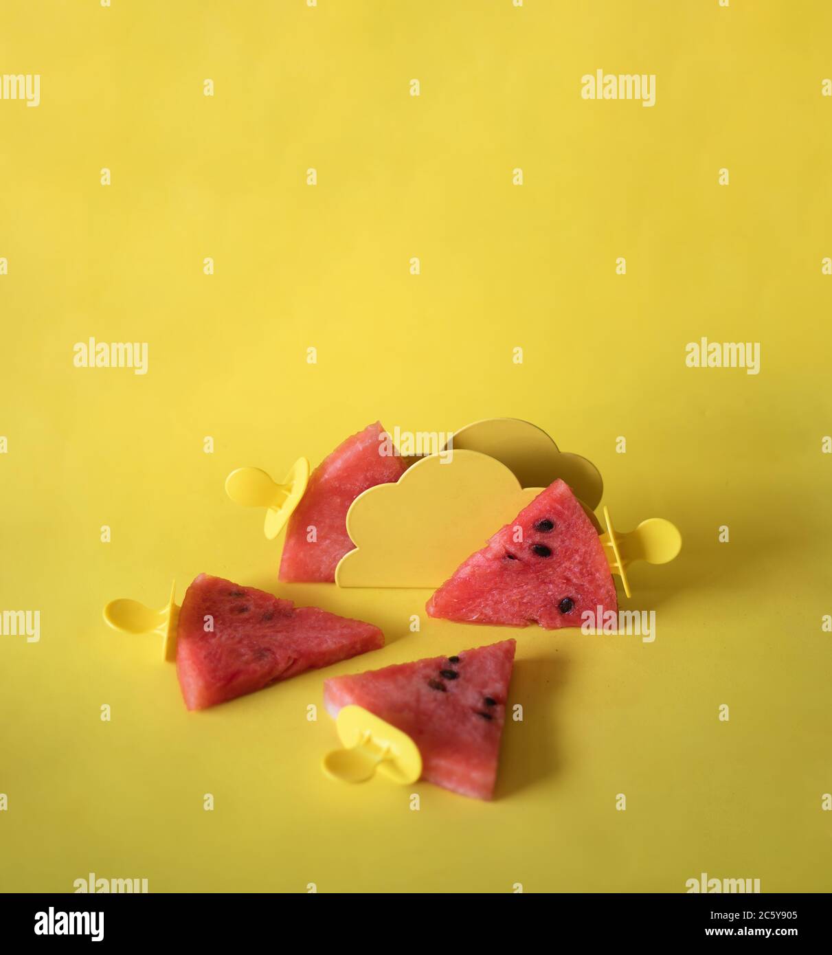 Watermelon slices on an ice cream stick on an yelloow background. Creative idea Stock Photo