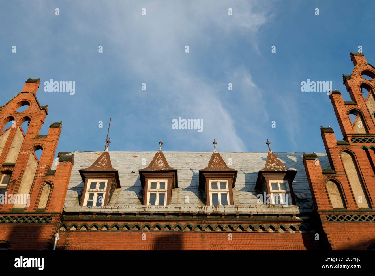 A detail of the red brick iconic, landmark train station mansard, dormer roof as the sun sets. In Klaipėda, Lithuania. Stock Photo