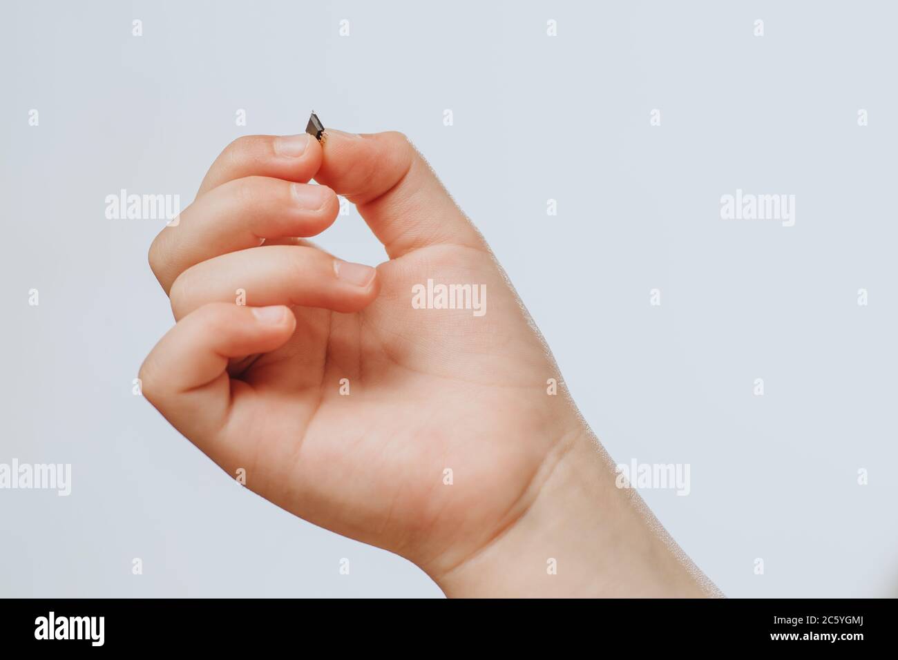 A small black chip holds a children's hand. Chipization of people after an epidemic coronavirus.  Stock Photo