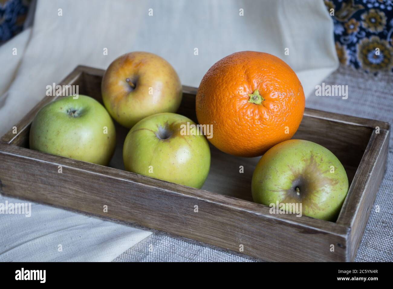 still life with apples and orange in a wooden box on a background of ...