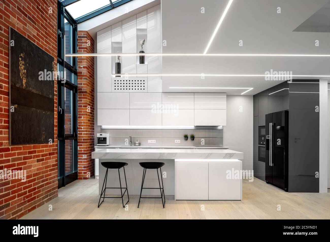 Elegant and modern kitchen in white with brick wall and big windows ...