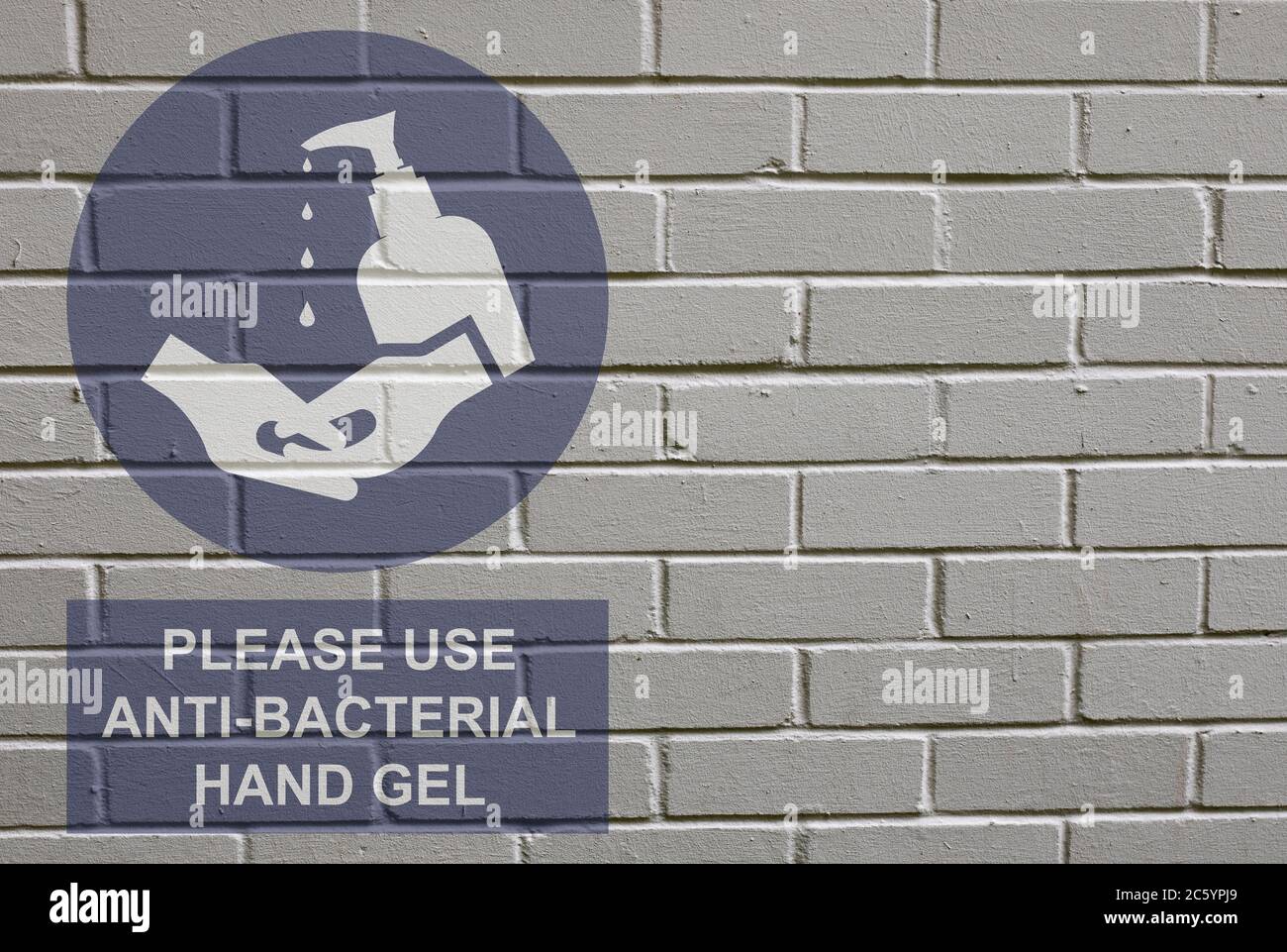 White decayed faded brick wall background with please use anti bacterial hand gel sign to stop the spread of the worldwide pandemic Stock Photo