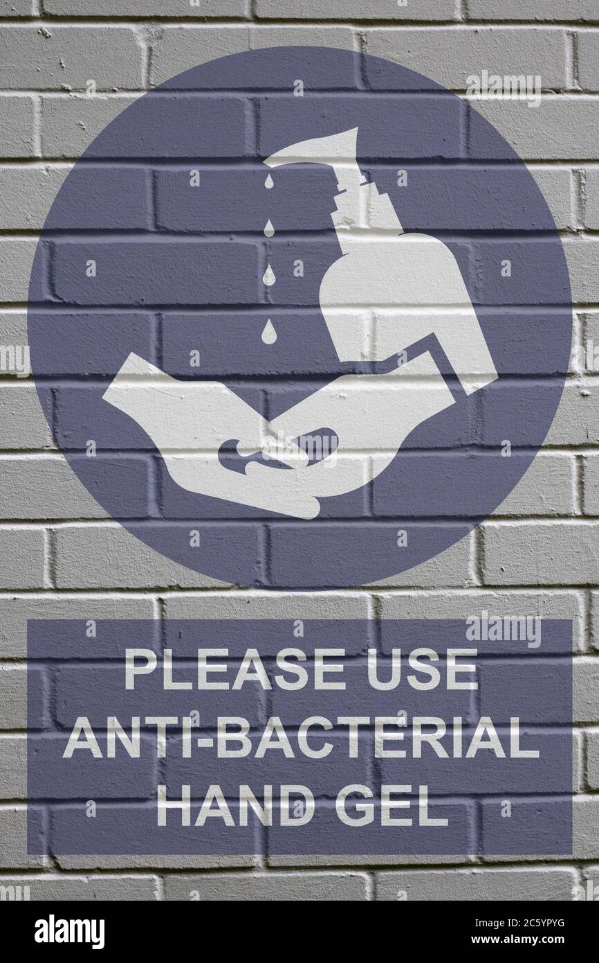 White decayed faded brick wall background with please use anti bacterial hand gel sign to stop the spread of the worldwide pandemic Stock Photo