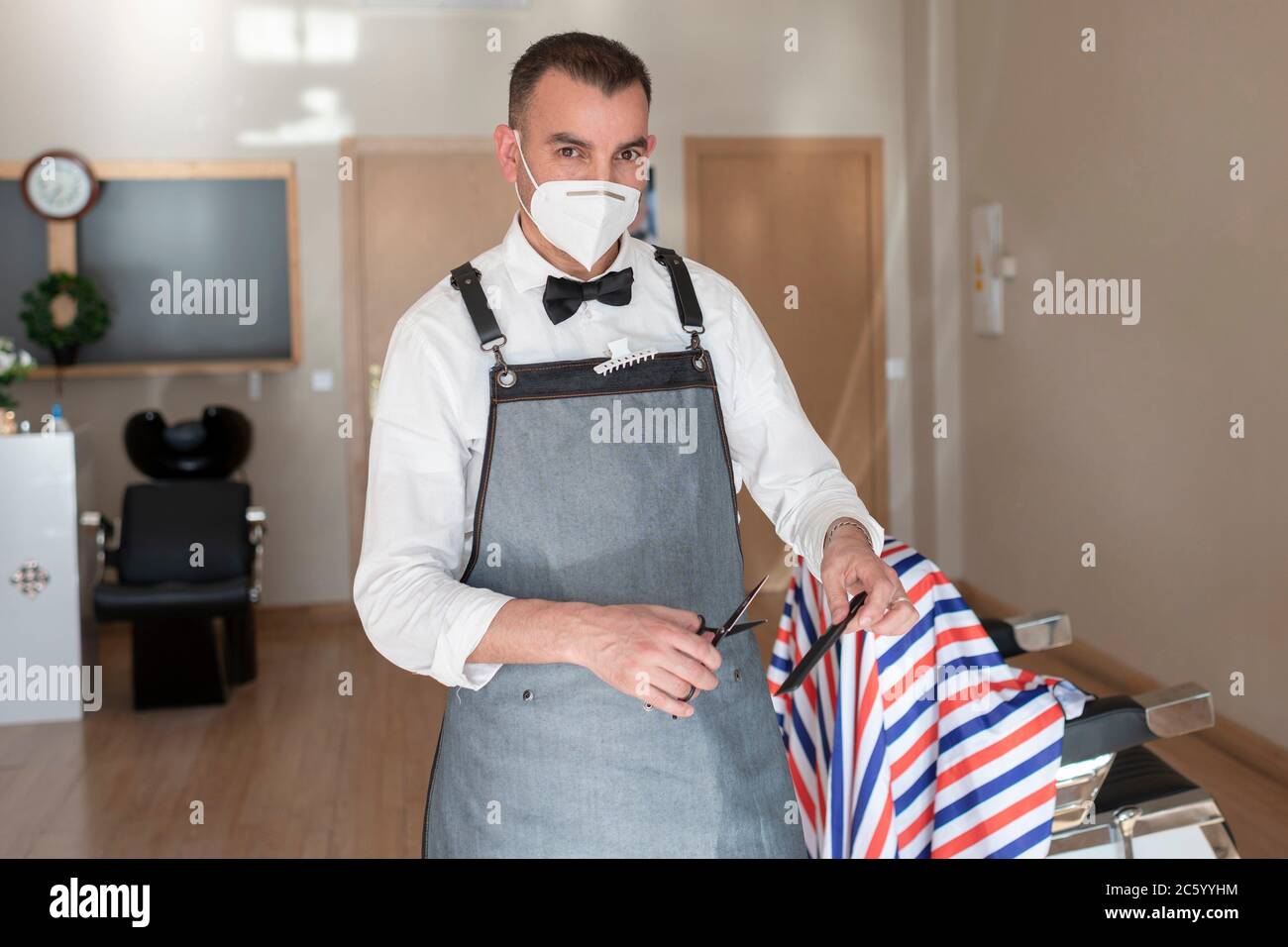 hairdresser prepared to cut hair in wearing face mask due to corona virus pandemic