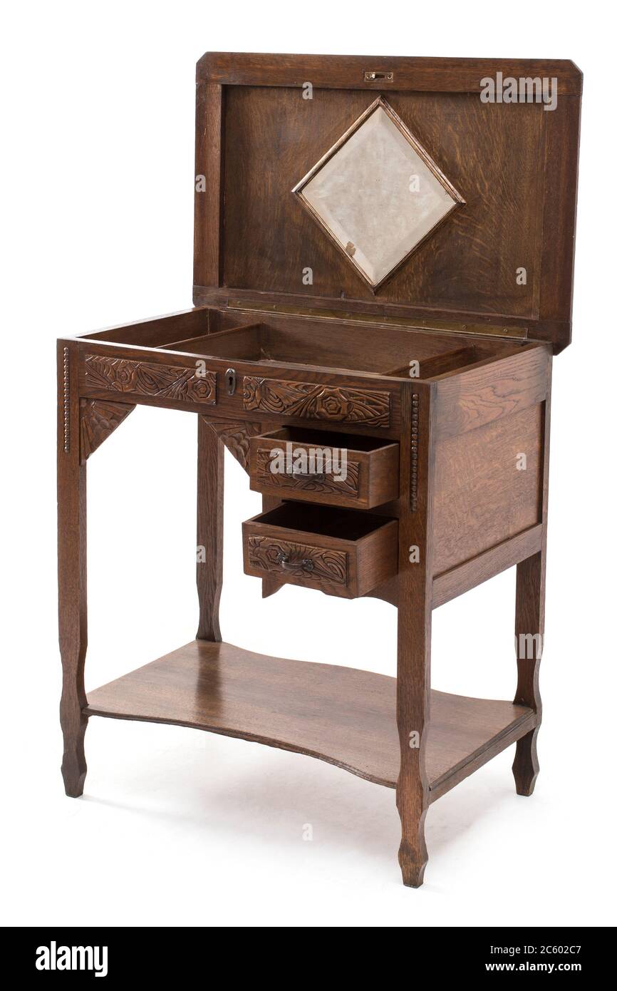 Antique wooden writing desk with drawers and wood carvings on the white background. Stock Photo