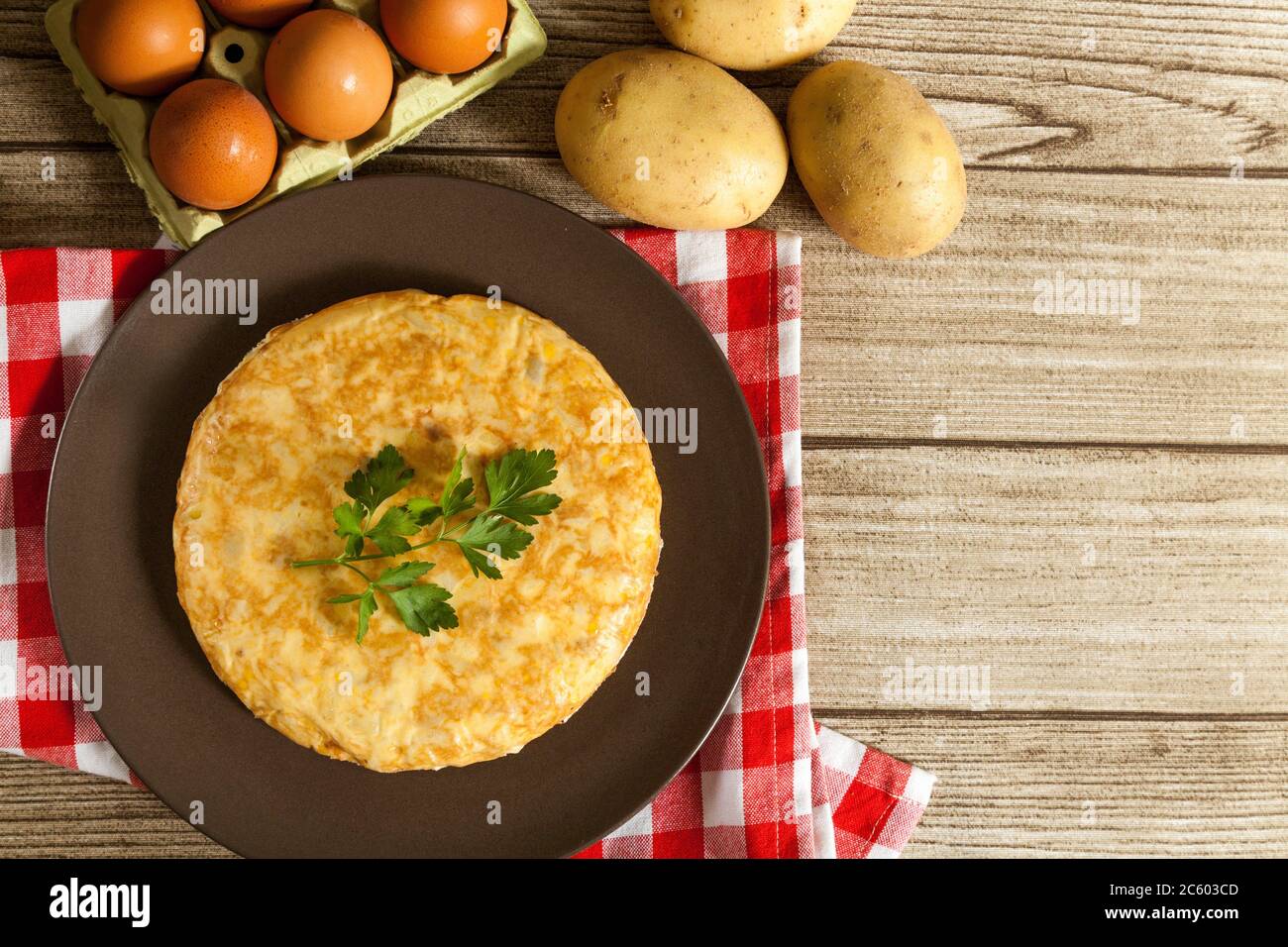 Spanish omelette in a plate, potatoes and eggs on wooden table from