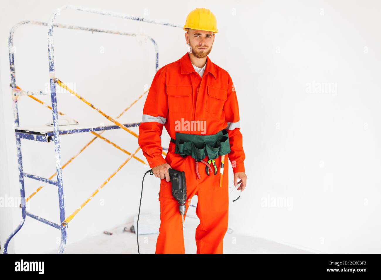 Young builder in orange work clothes and yellow hardhat looking Stock Photo