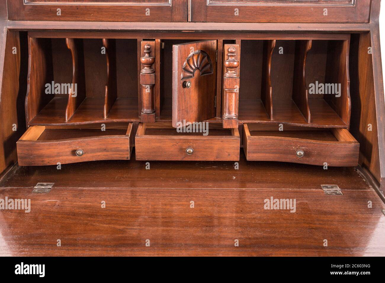 Antique wooden writing desk with drawers and wood carvings on the white background. Stock Photo