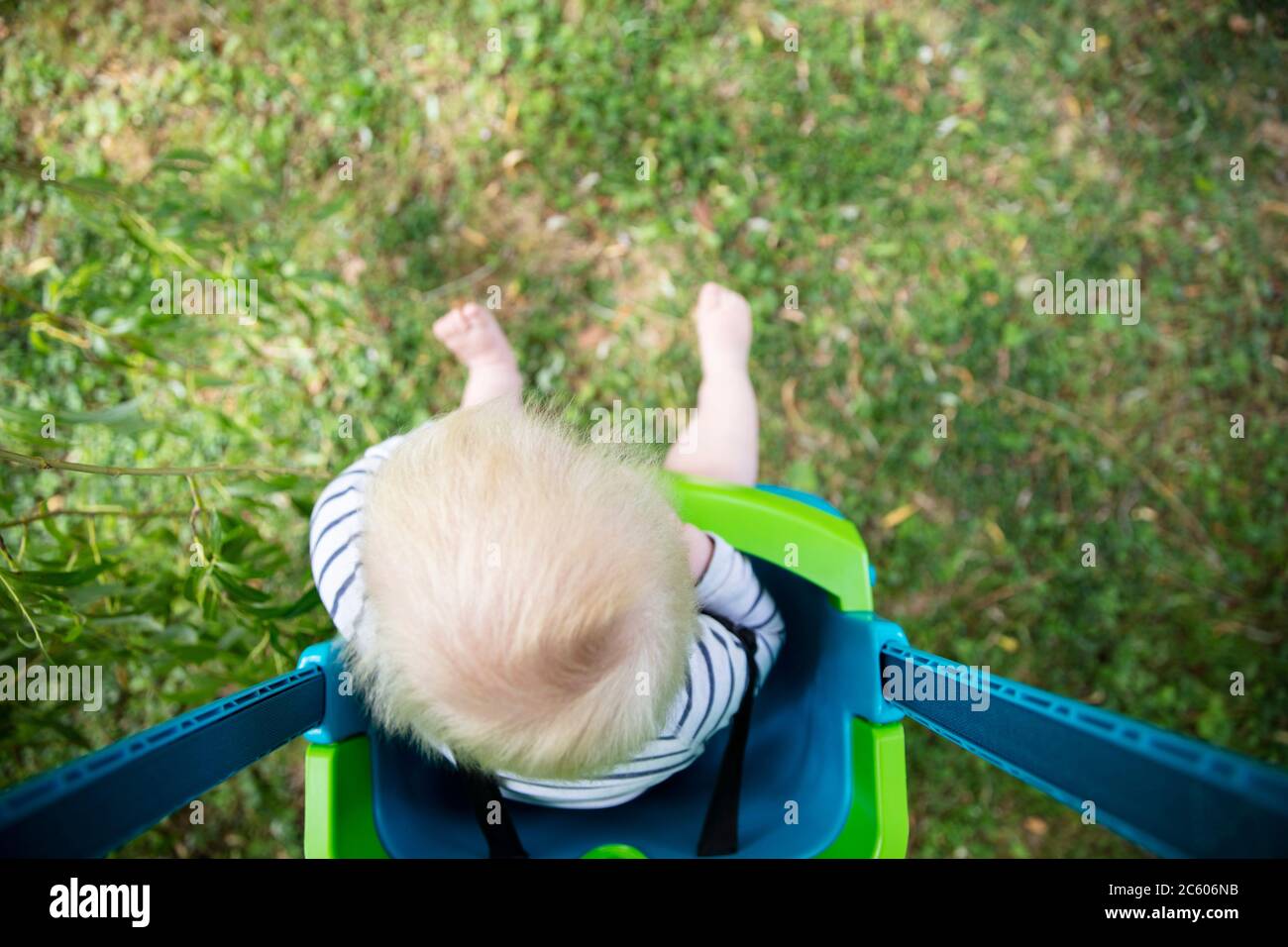 A little boy having fun playing on a swing under a tree in a garden Stock Photo