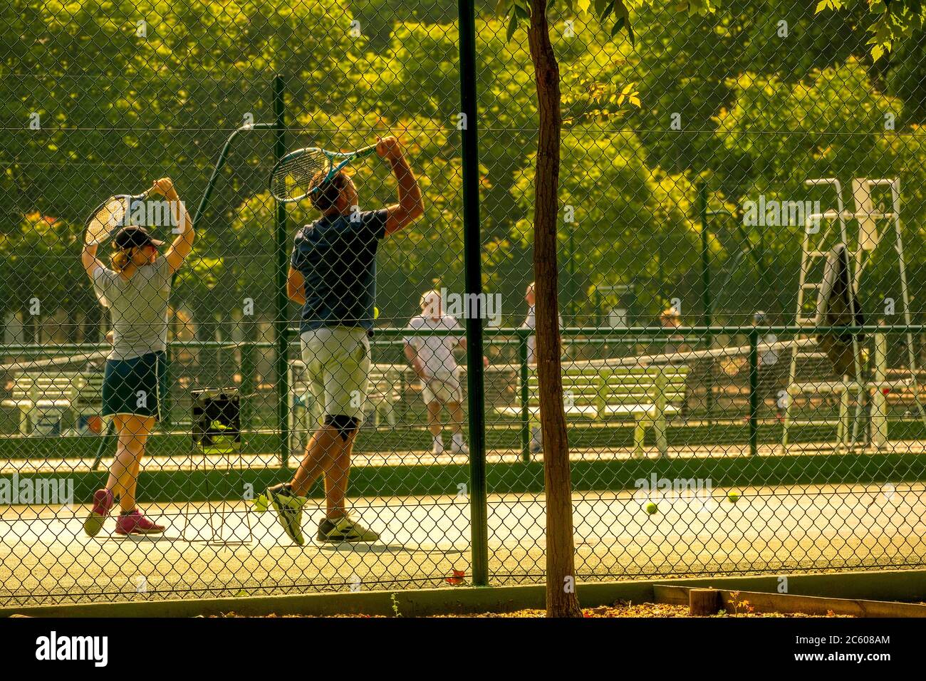 Sunny summer day at the tennis court. Defocused figures of a girl and her trainer Stock Photo