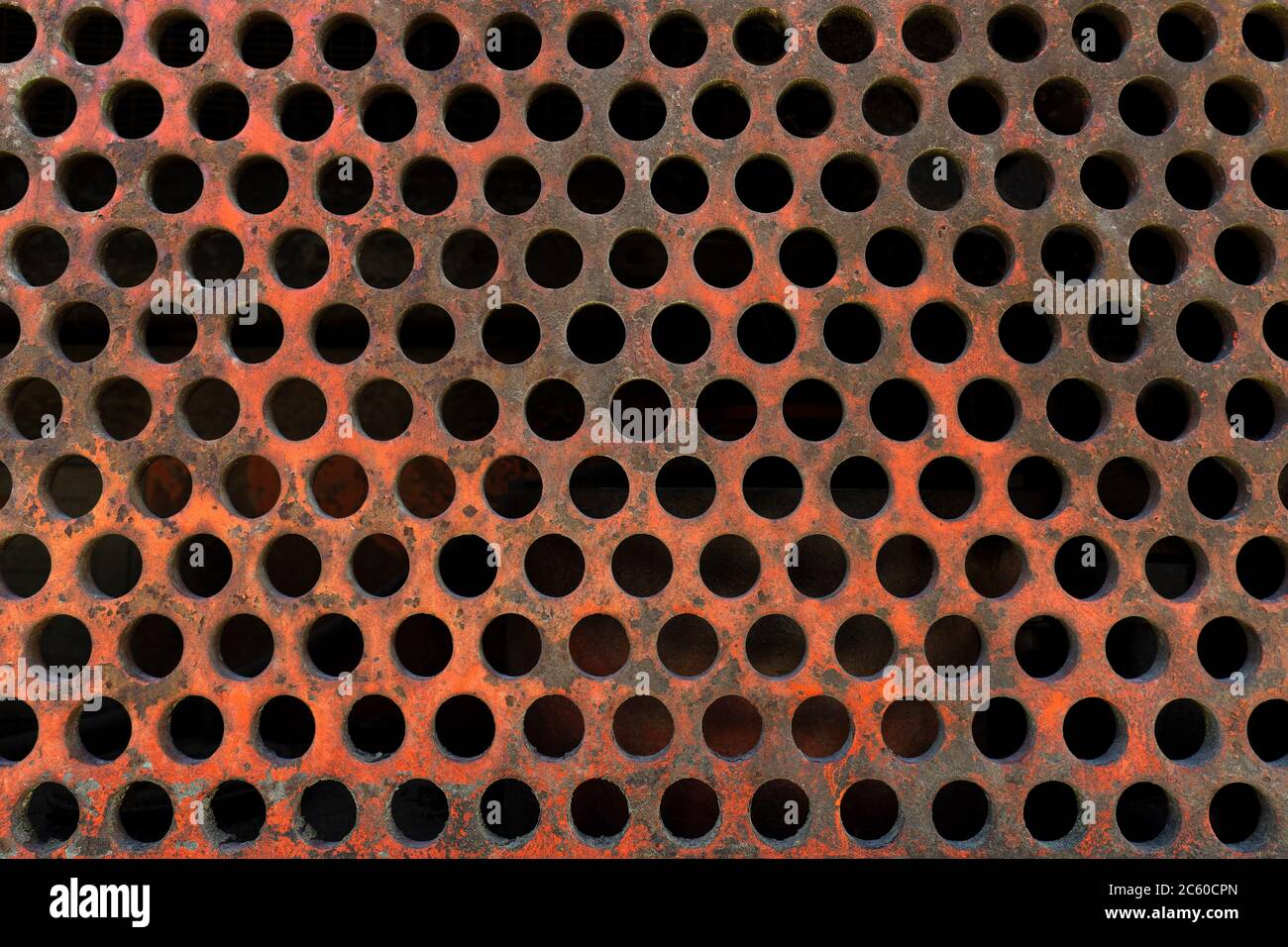 Very old, rusty, reddish perforated plate Stock Photo