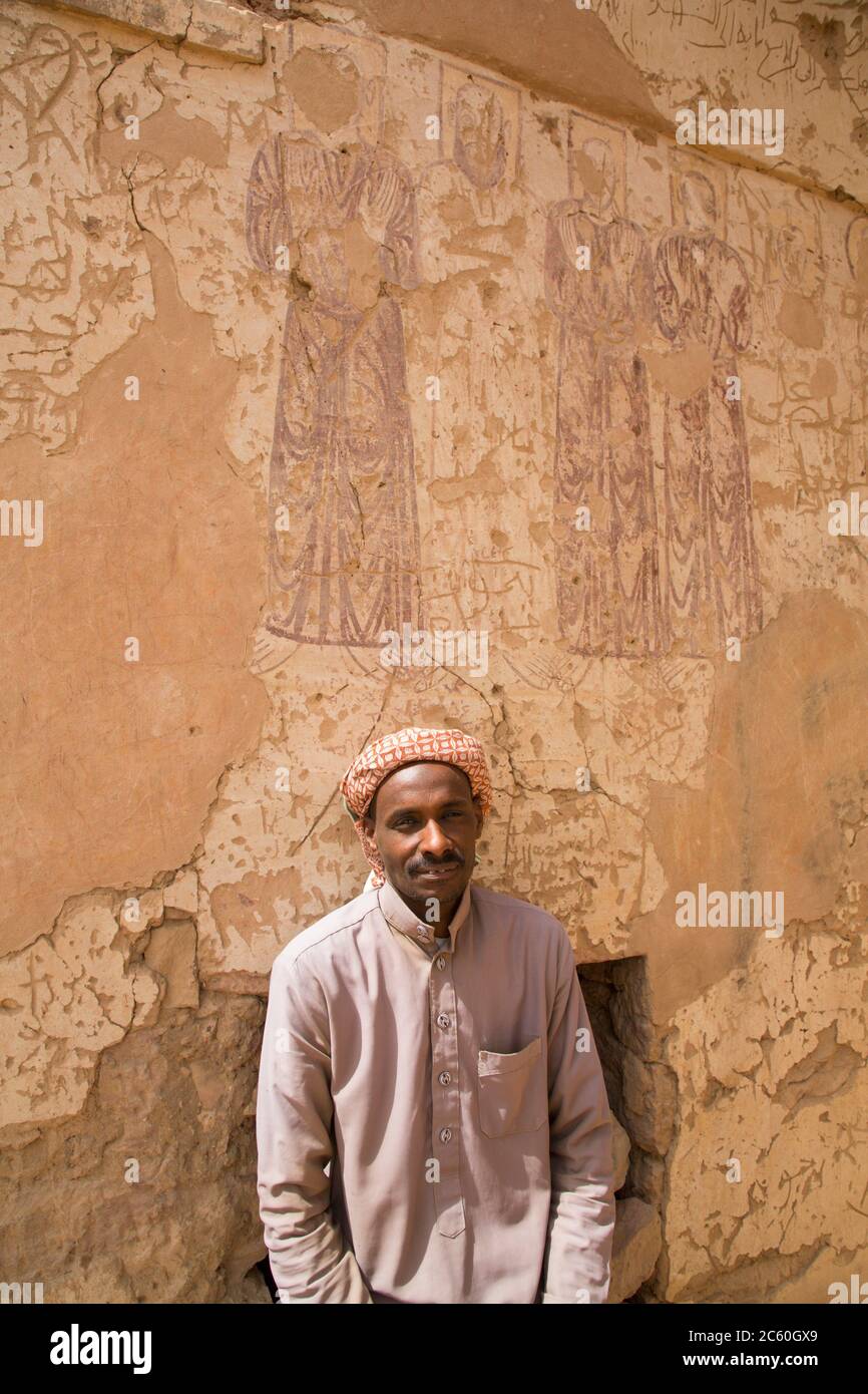 Caretaker, Murals (background), Coptic Chapel, Tombs of the Nobles, Aswan, Egypt Stock Photo