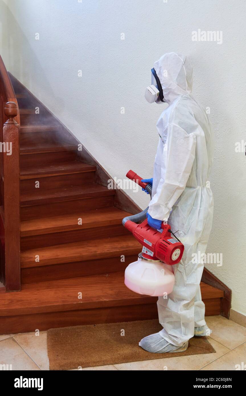 Worker in protective suit disinfect interior office. Stock Photo