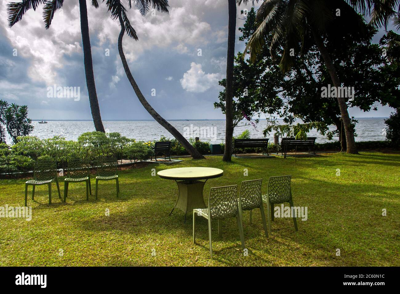 chairs and table in a lawn of a resort on the bank of Vembanad lake Kerala Stock Photo