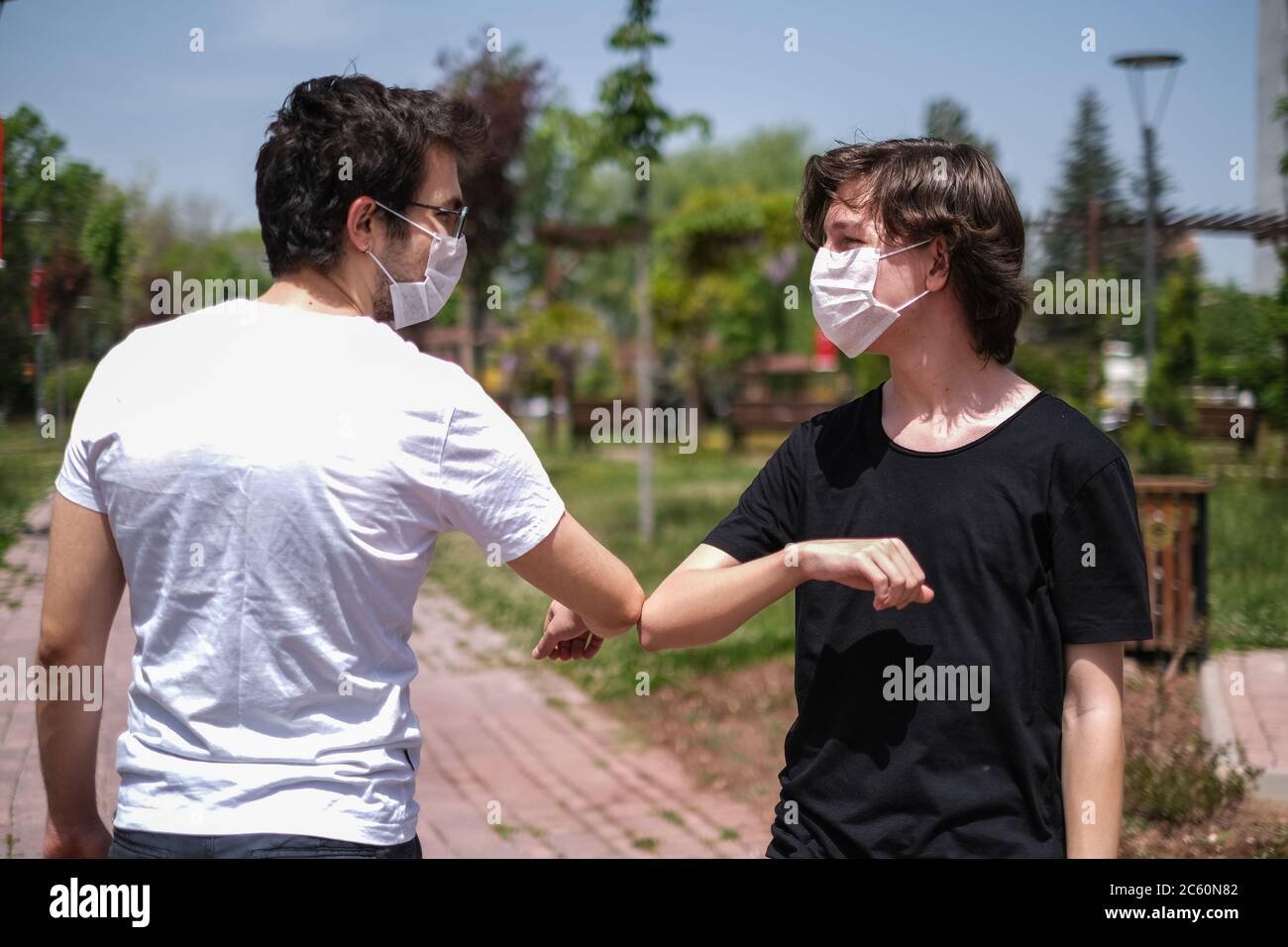 Greeting with elbow in coronavirus epidemic days. New greeting style during coronavirus epidemic. Two friends bump elbows outdoors. Stock Photo