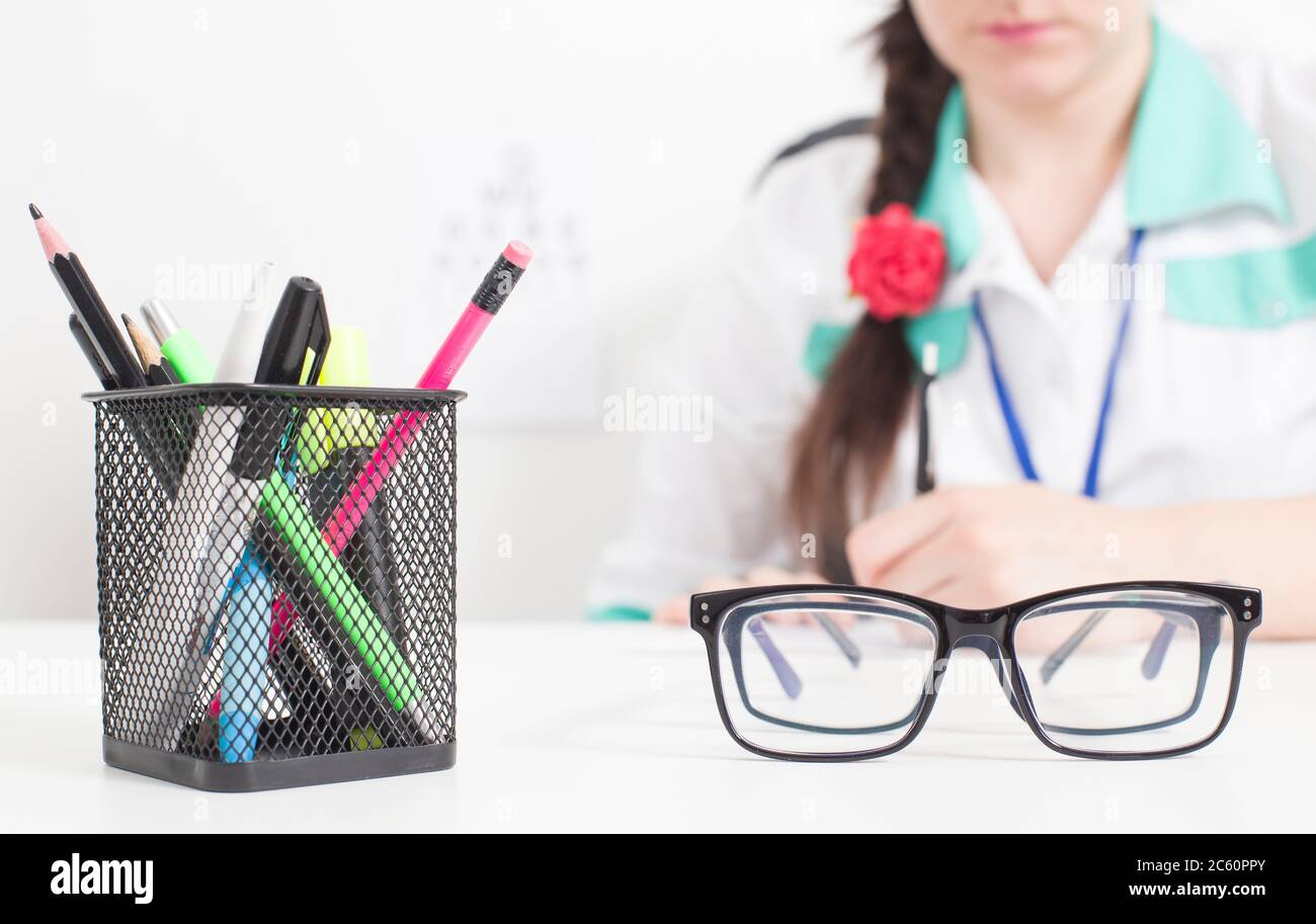 Glasses for the eyes in the foreground, in the background the doctor an ophthalmologist writes out a prescription in the doctor s office, conjunctivit Stock Photo