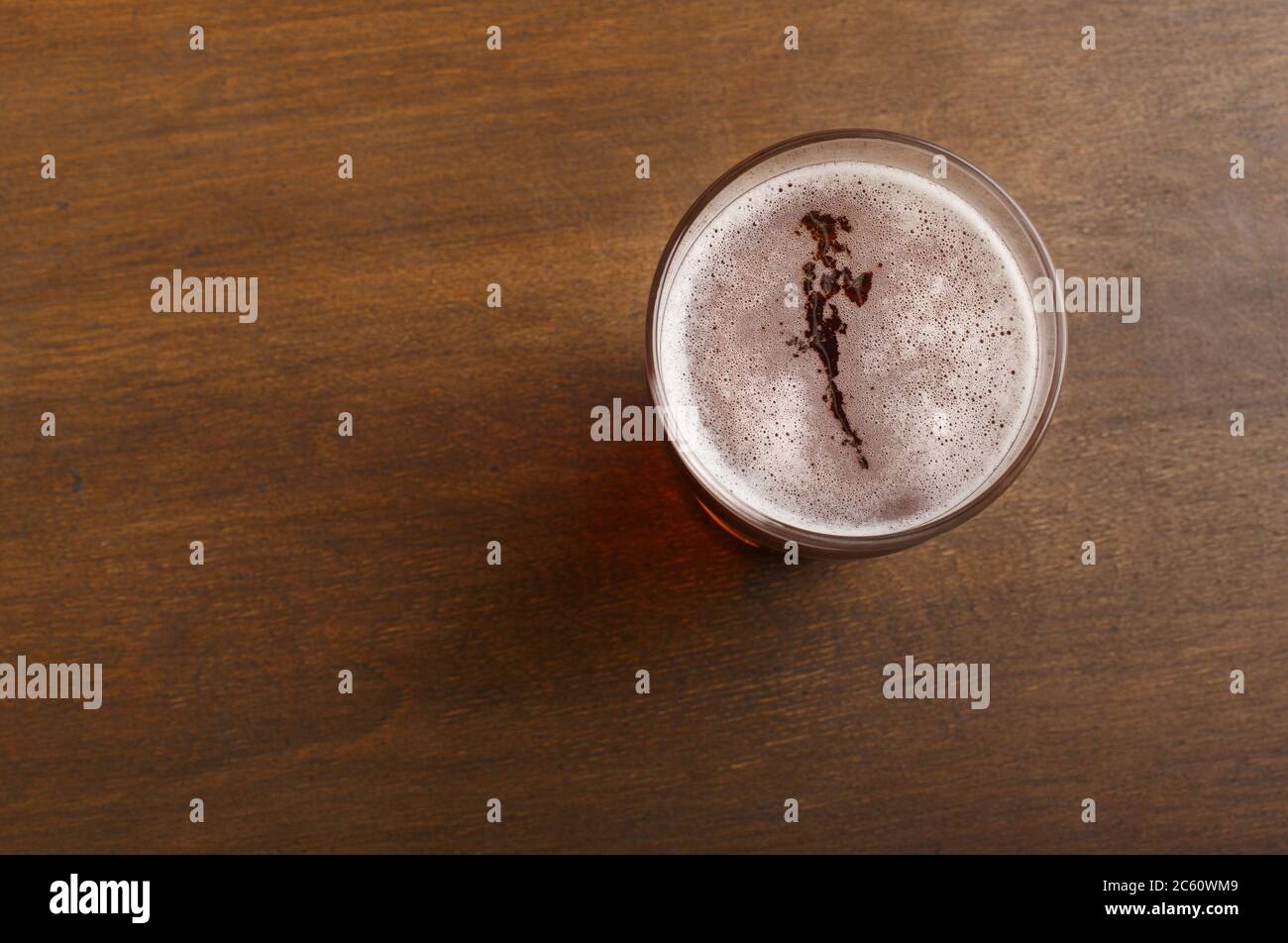 Craft beer in pub. Drink with foam in glass on brown wooden table Stock Photo