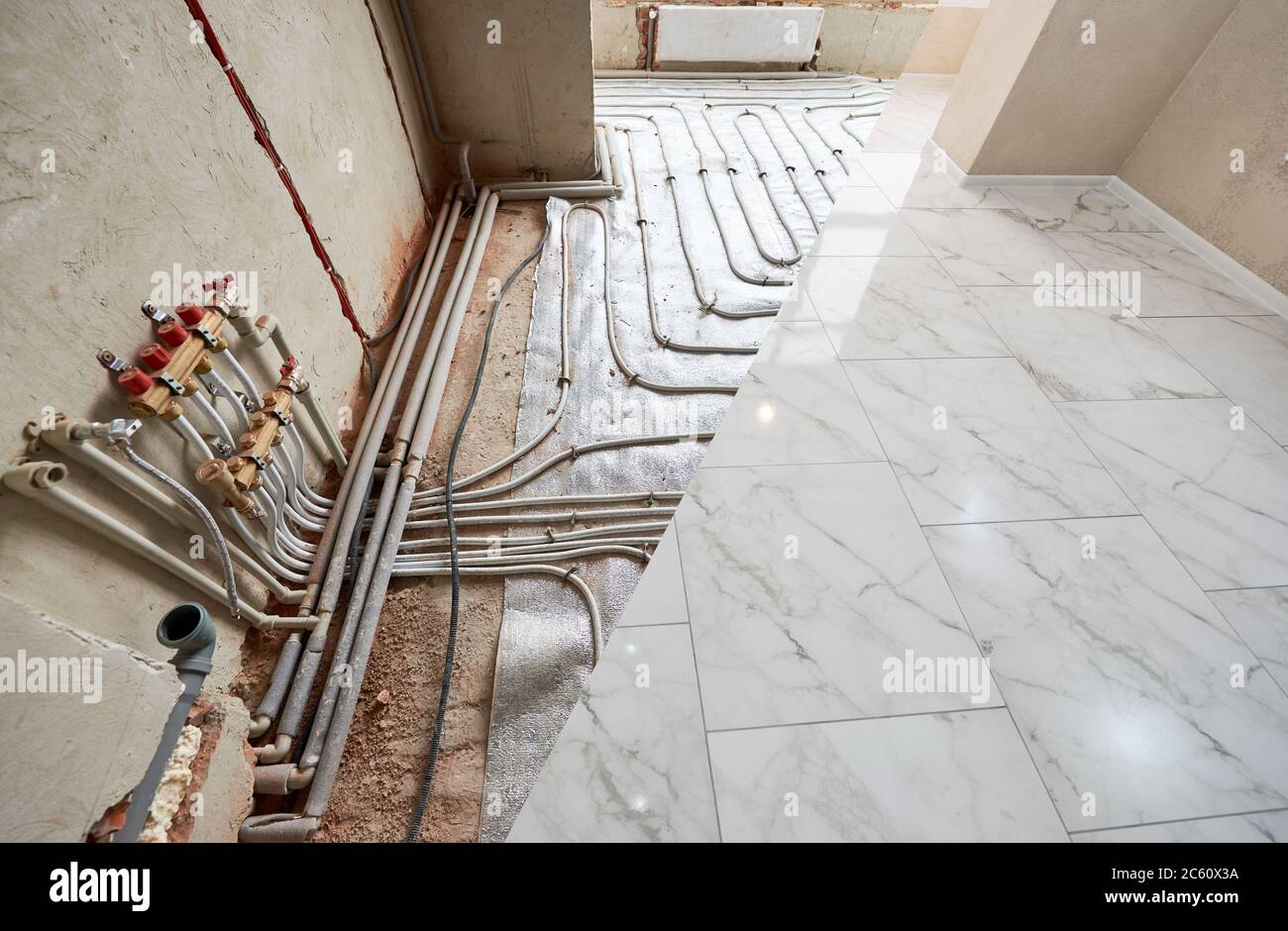 Snapshot of a floor before and after renovation. Conduction of pipes for floor heating system vs new white shiny tiles on the floor in spacious room. Concept of home renovation and restoration. Stock Photo