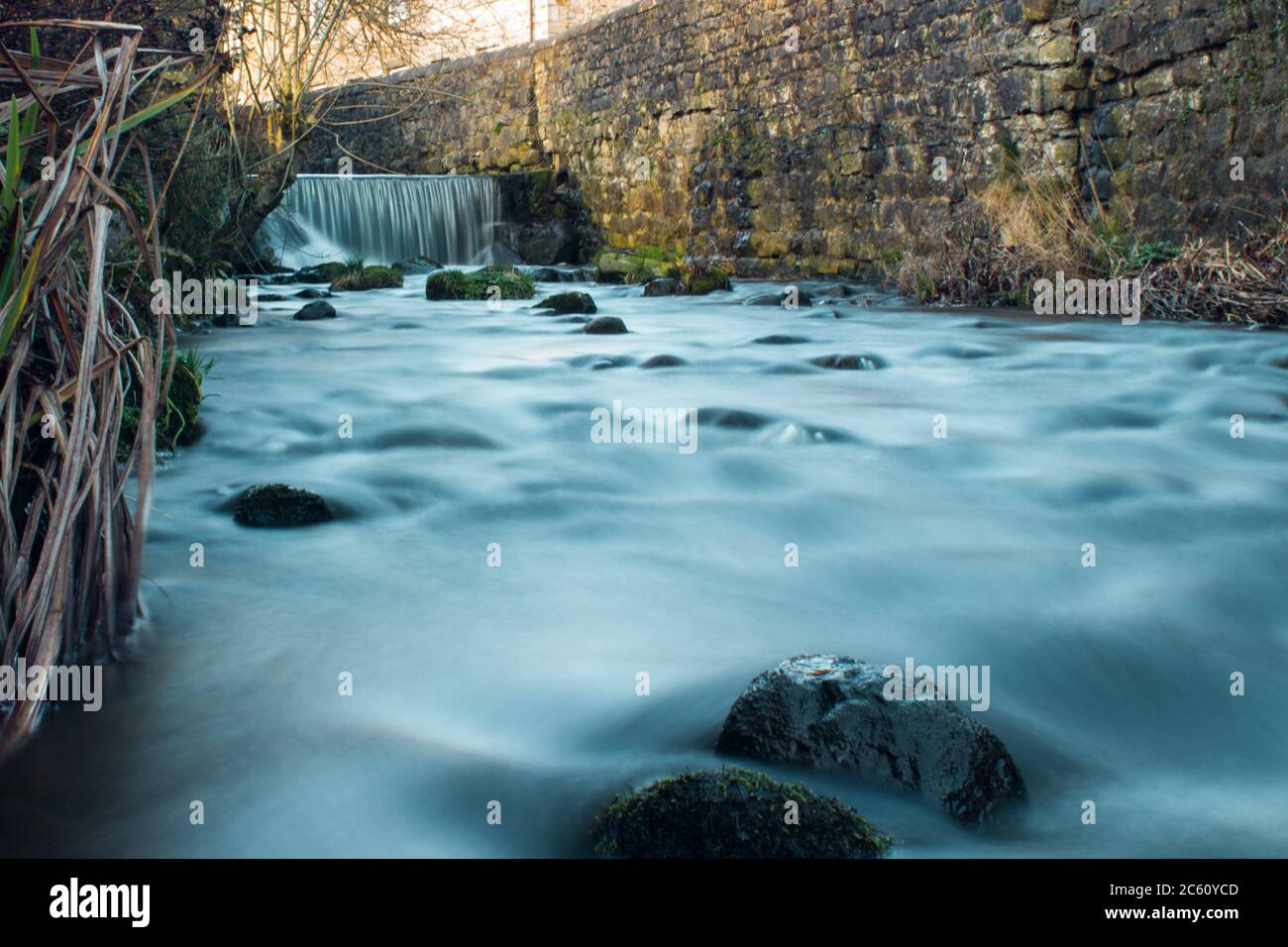 Smooth flowing stream with a waterfall in the backround. Ribble Valley. Stock Photo