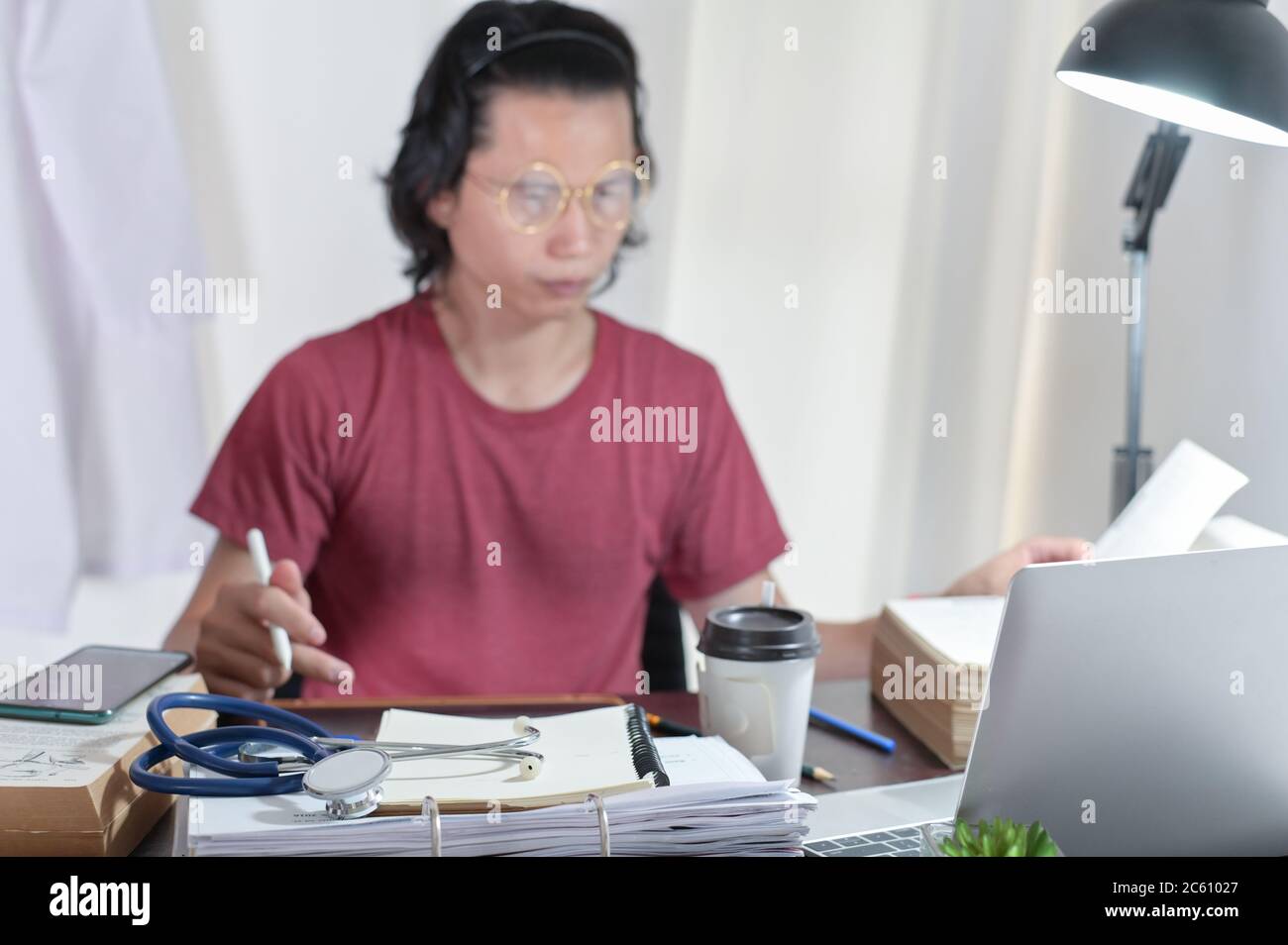 Doctors casual wearing reading medical books and researching online knowledge to find treatment patient guidelines In the doctor's room office,Focus Stock Photo