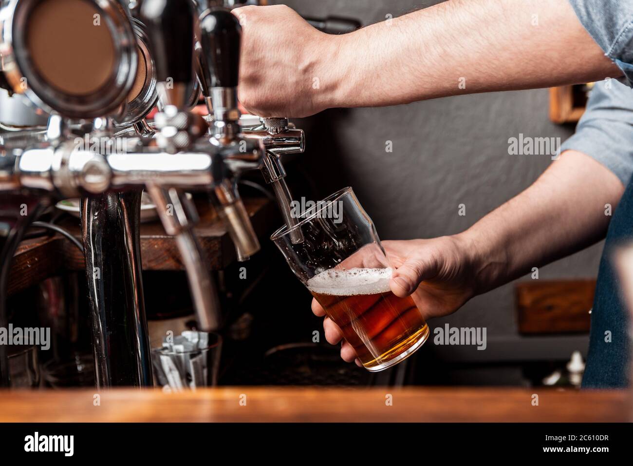 Craft beer from keg. Bartender pours beer in glass from tap Stock Photo