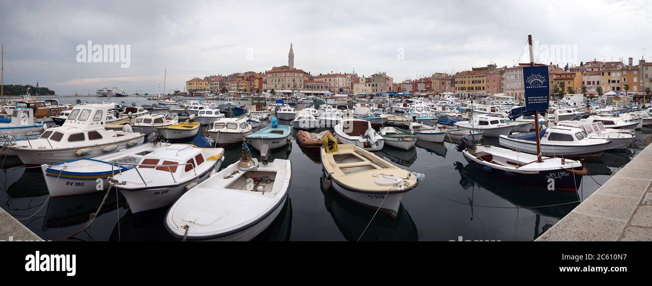 Rovinj, Croatia - August 31, 2007: Motorboats, boats and yachts on water in port of Rovinj. Medieval vintage houses of old town on the background. Stock Photo