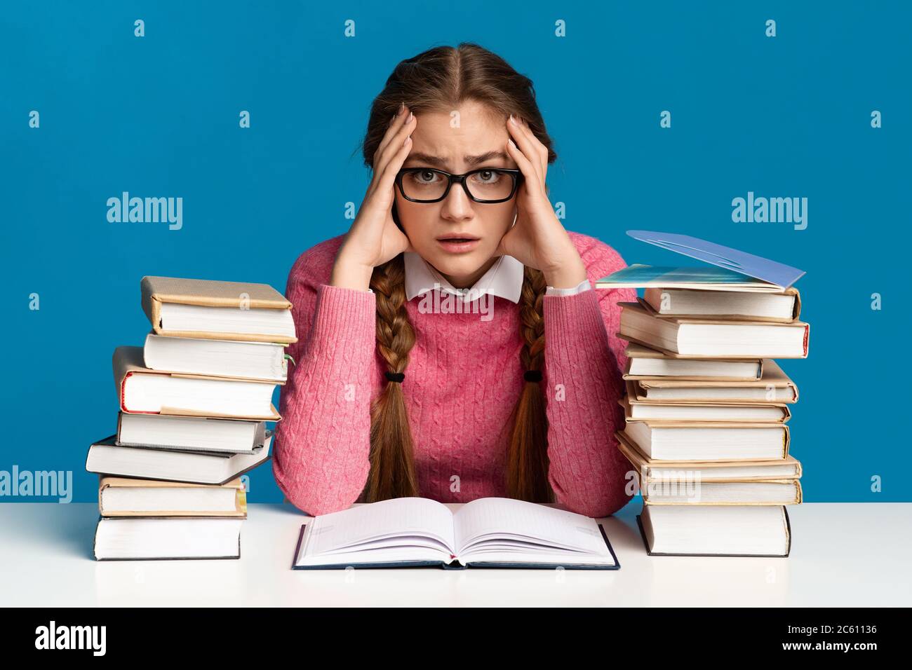 Exam preparation. Teen girl holding head among books Stock Photo