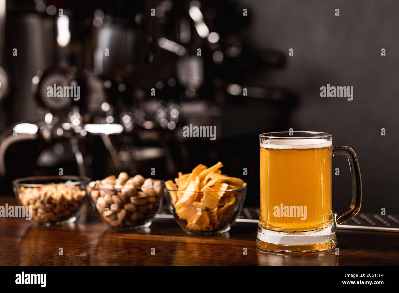 Craft beer festival. Pistachios, chips and nuts in glass plates and beer in mug in interior Stock Photo