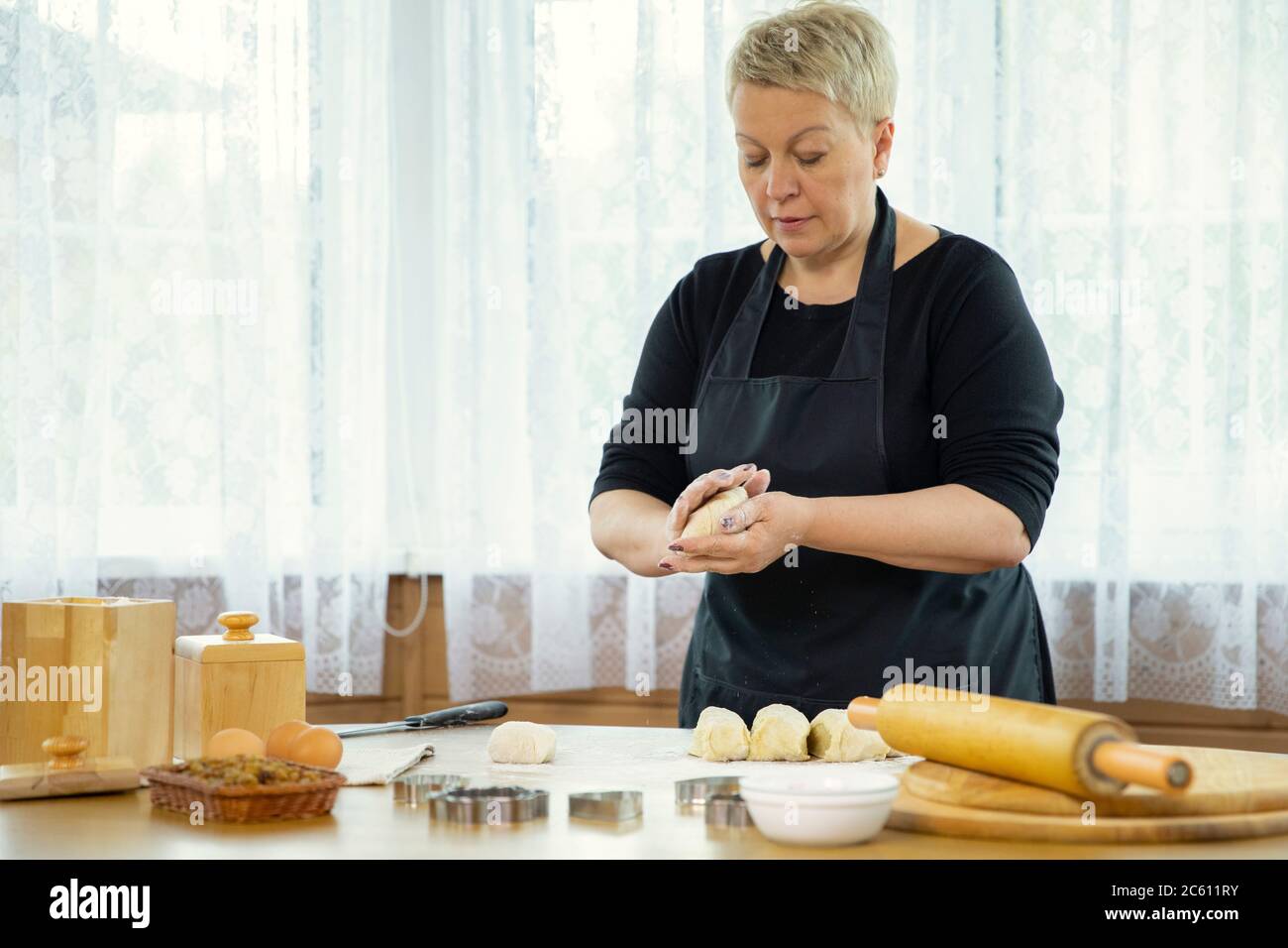Female baker cooking buns, woman making dough for dumplings, empanadas Stock Photo